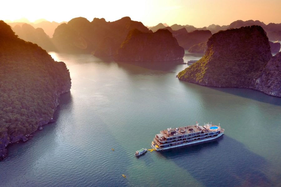 Premium Lan Ha Bay cruise anchored between limestone mountains at golden hour